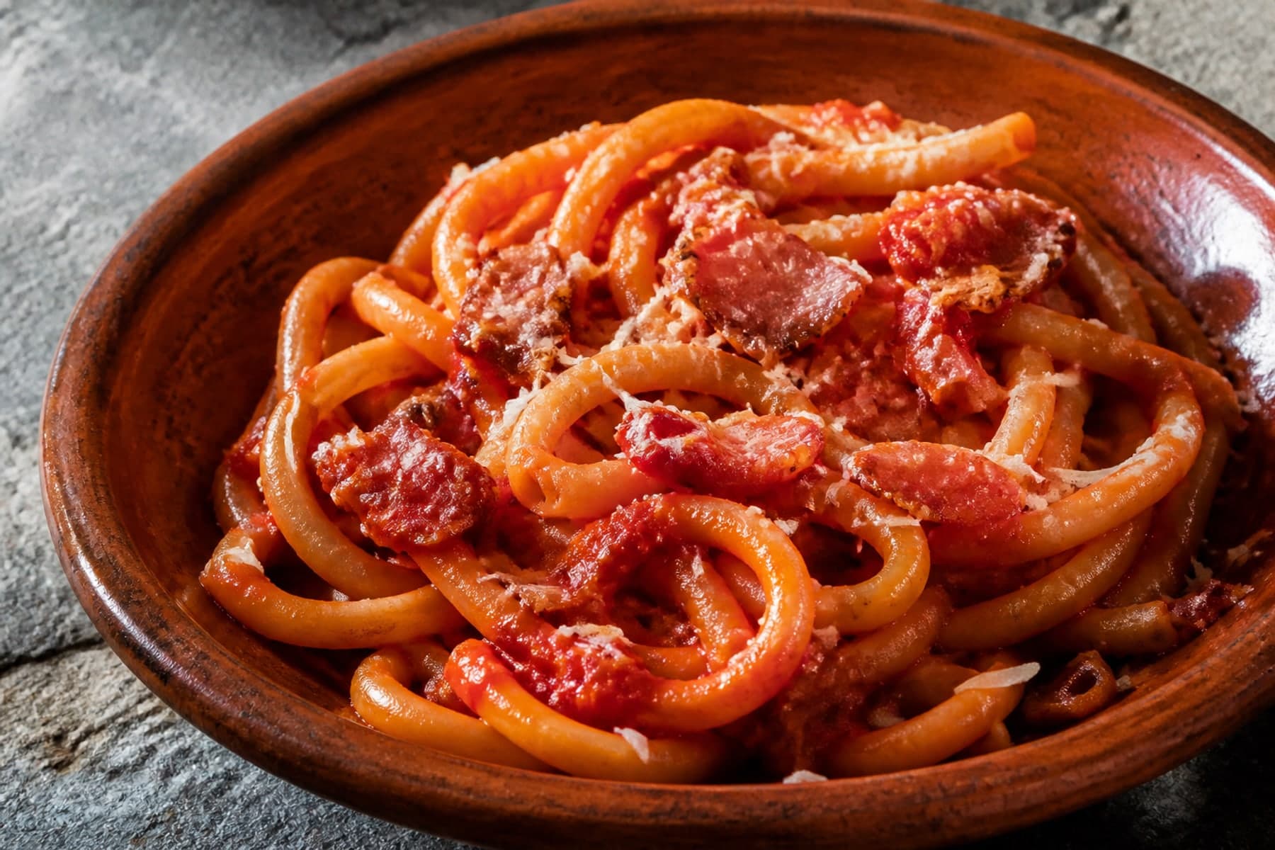 Bucatini all amatriciana in a terracotta bowl with tomato sauce and guanciale