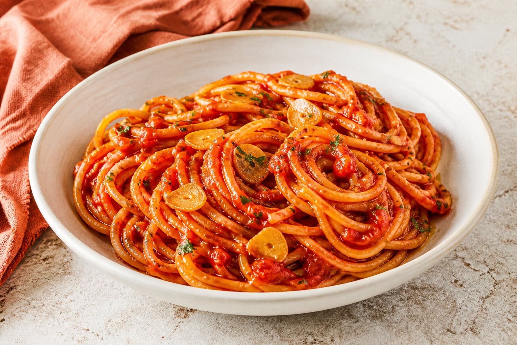 Spaghetti coated in concentrated tomato garlic sauce with parsley