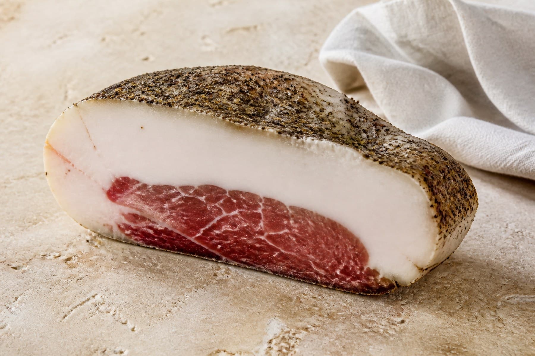 Cross-section of cured pork jowl showing a broad white fat layer and seasoned meat