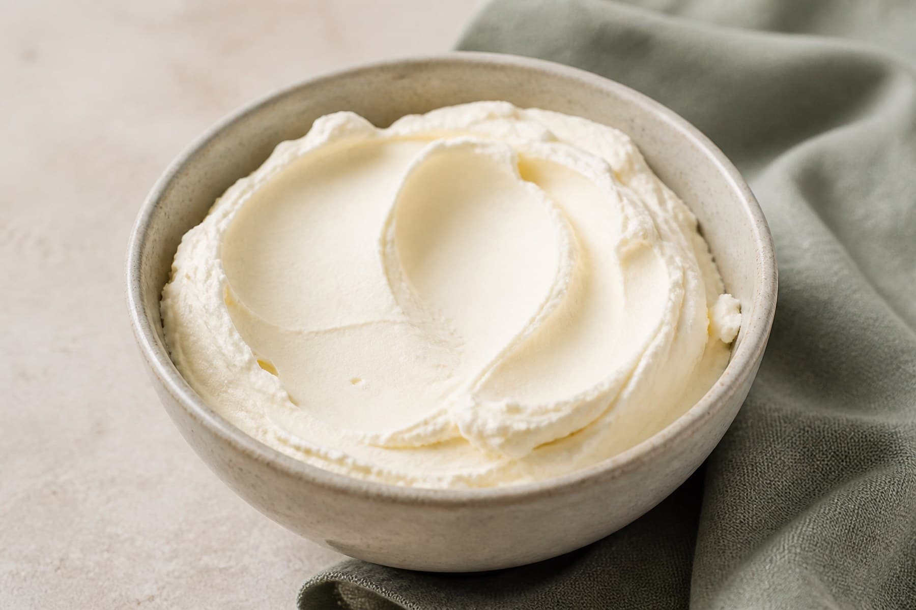 Thick ivory mascarpone with soft spoon marks in a plain ceramic bowl
