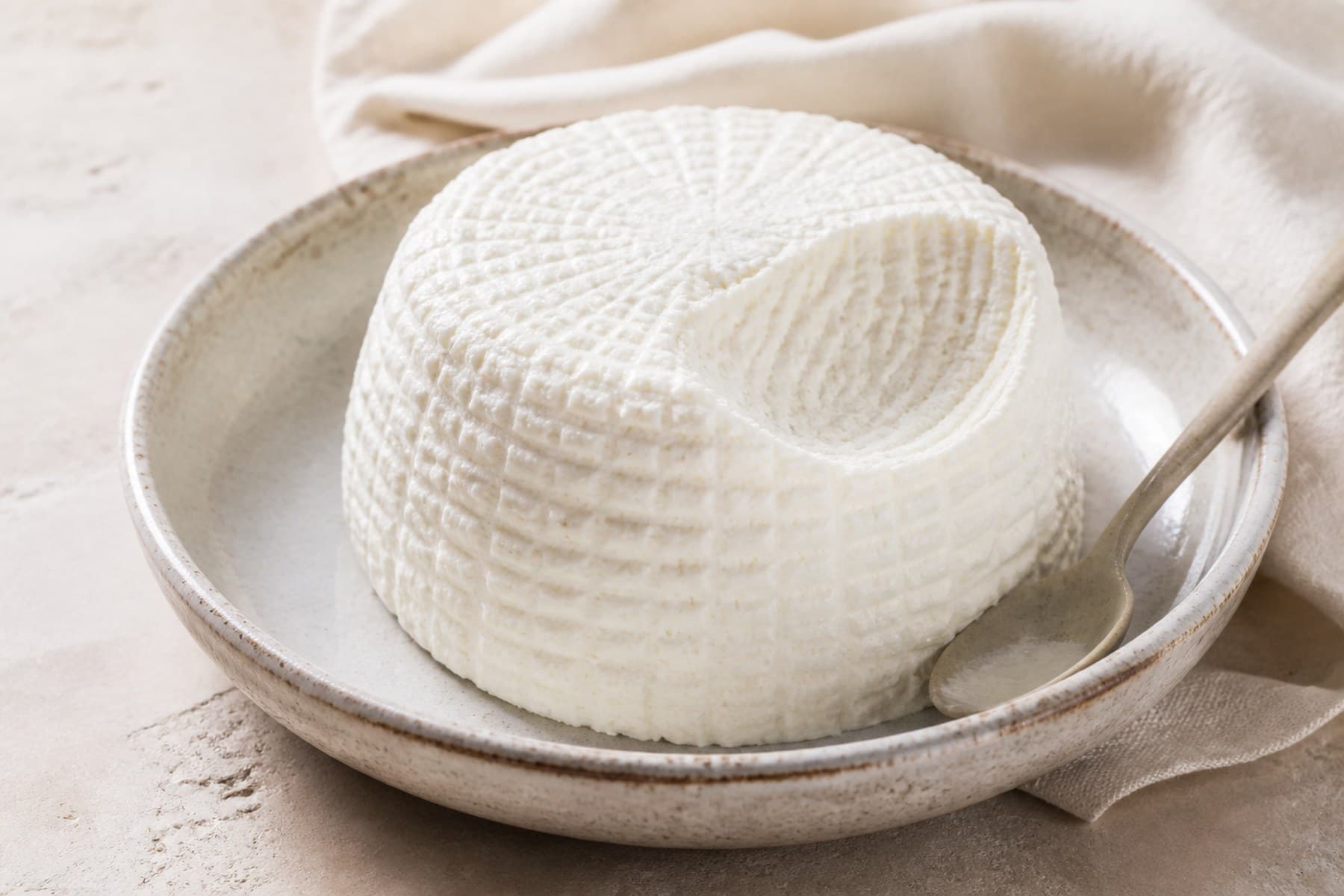 Fresh white ricotta with a delicate basket texture in a ceramic dish