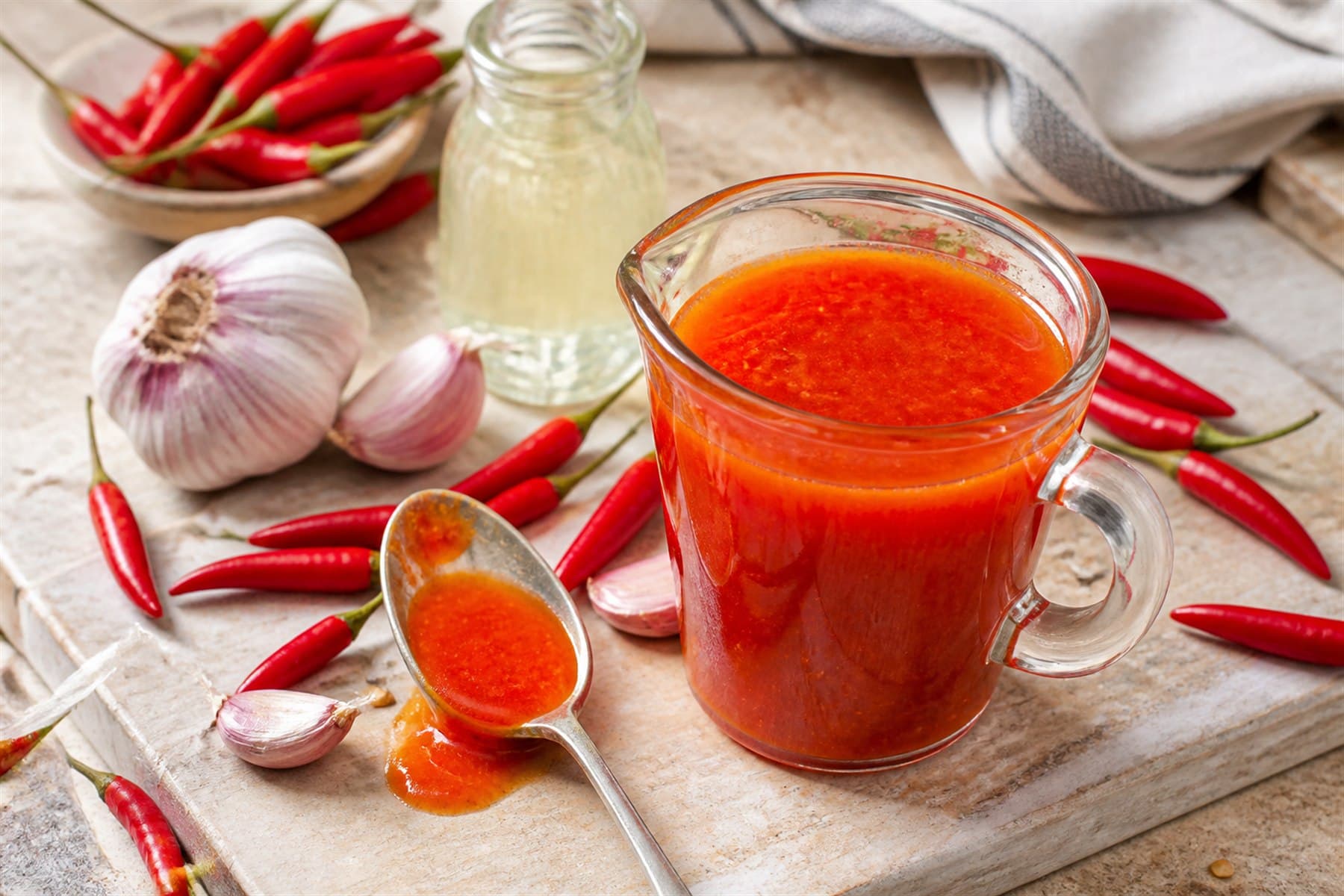 Fresh red homemade chilli sauce in a clean glass jar with chillies