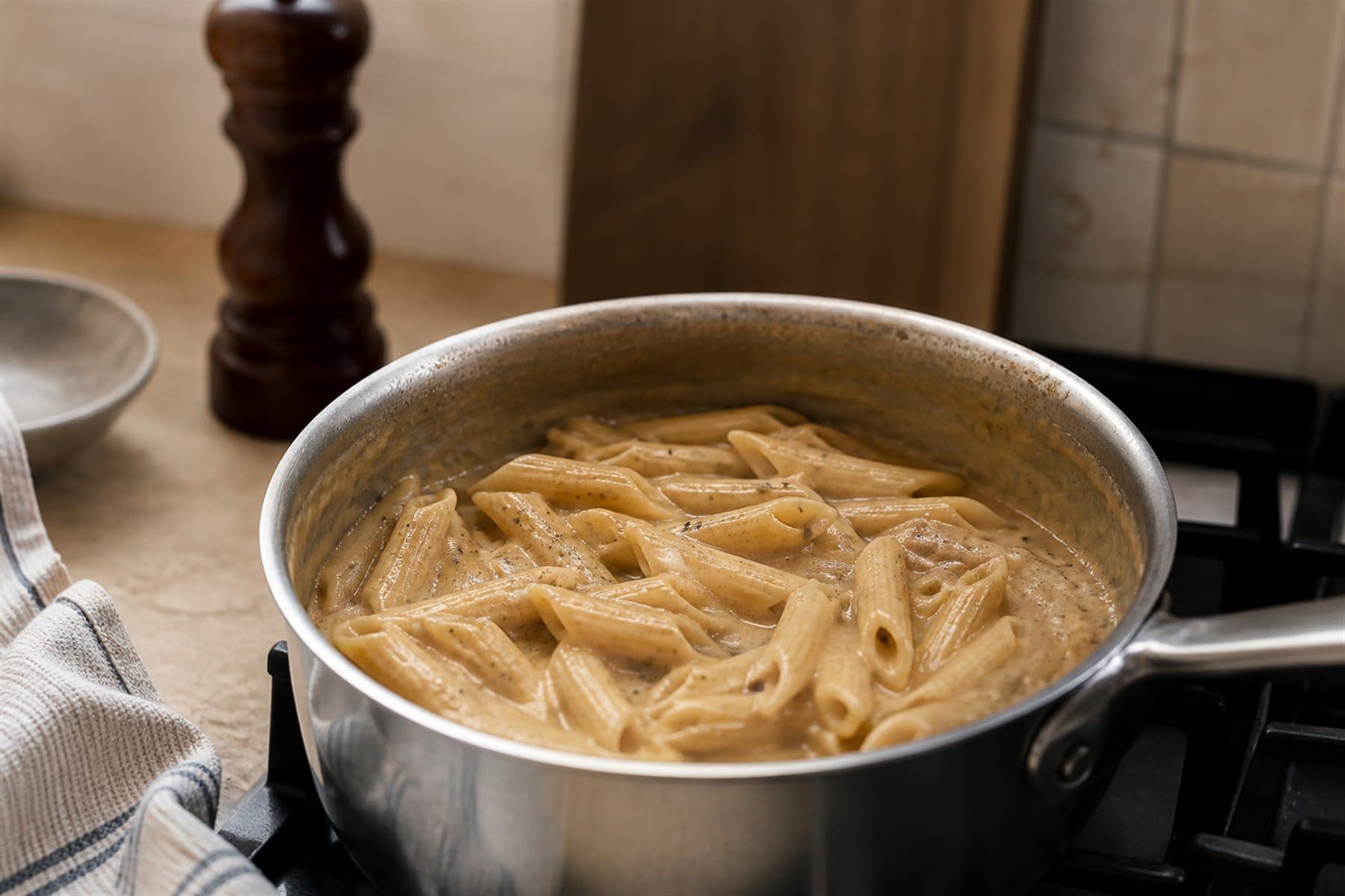 Black pepper cream sauce with visible cracked pepper in a small pan