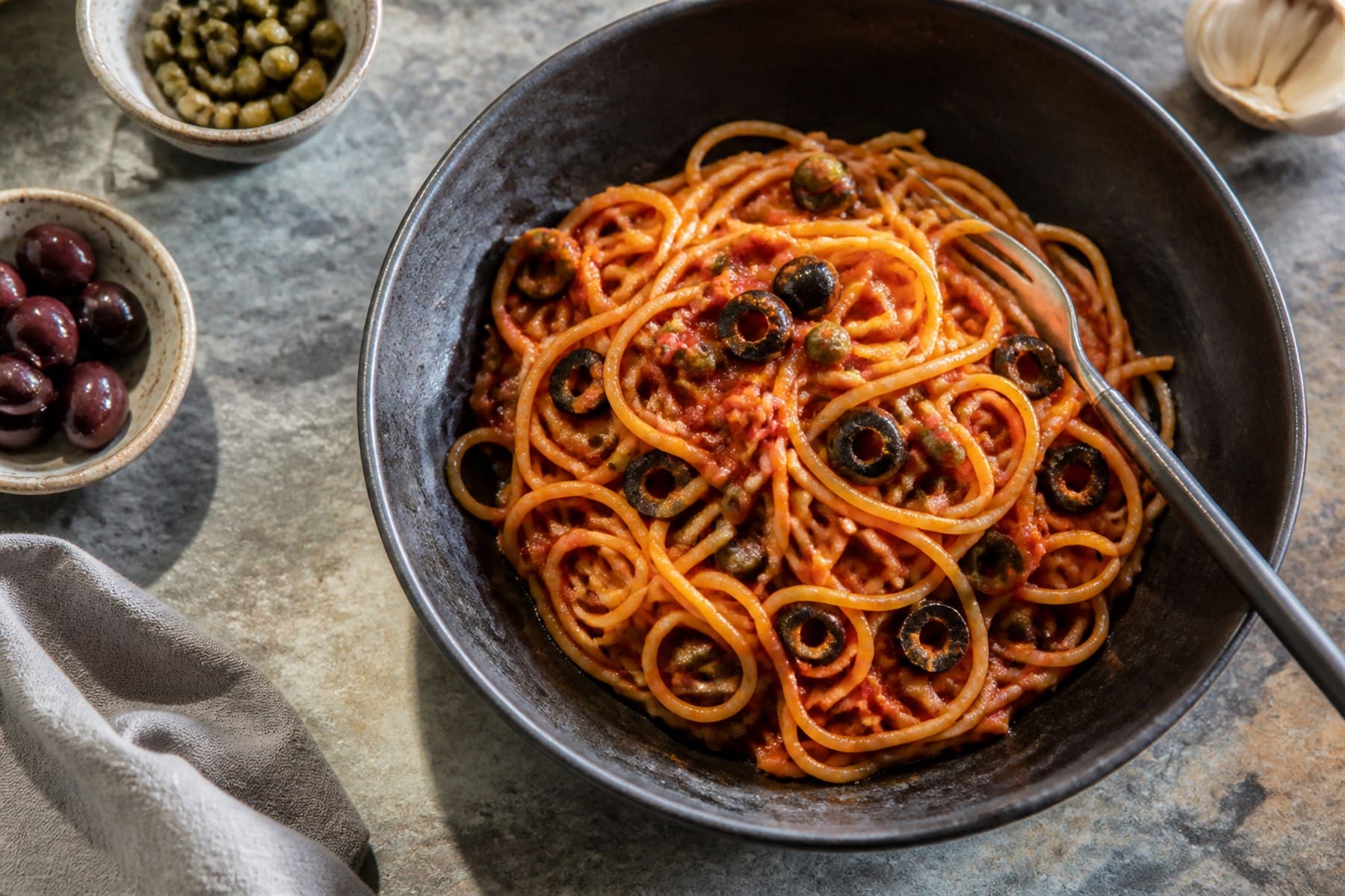 Puttanesca sauce with olives and capers coating spaghetti